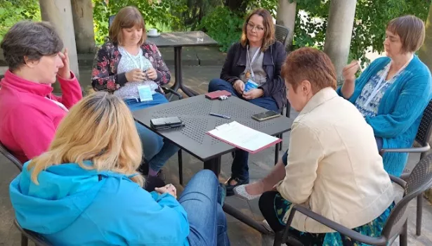 Na zdjęciu widać stół, przy którym siedzą osoby wspólnie dyskutujące